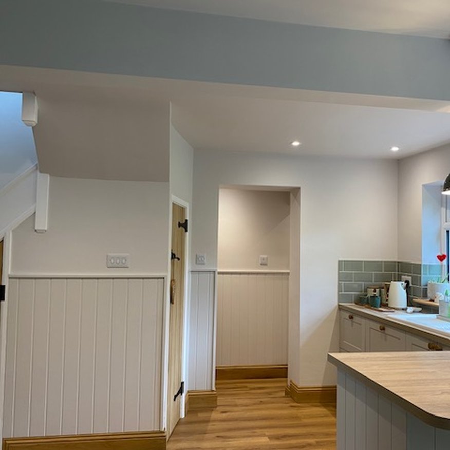 A person painted kitchen walls using a paintbrush and roller. The person applied the paint using Easy care Dulux paint onto the walls and woodwork
